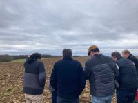 In a field, a group of 5 people watch a document